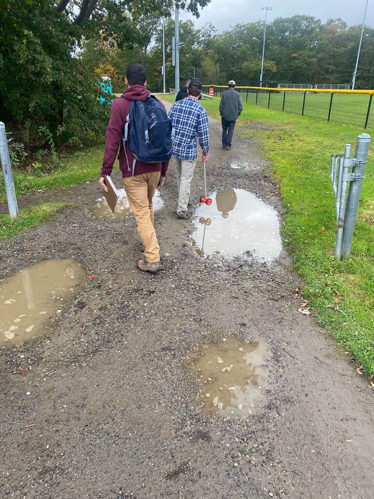 Three people walking among puddles at Payson Park